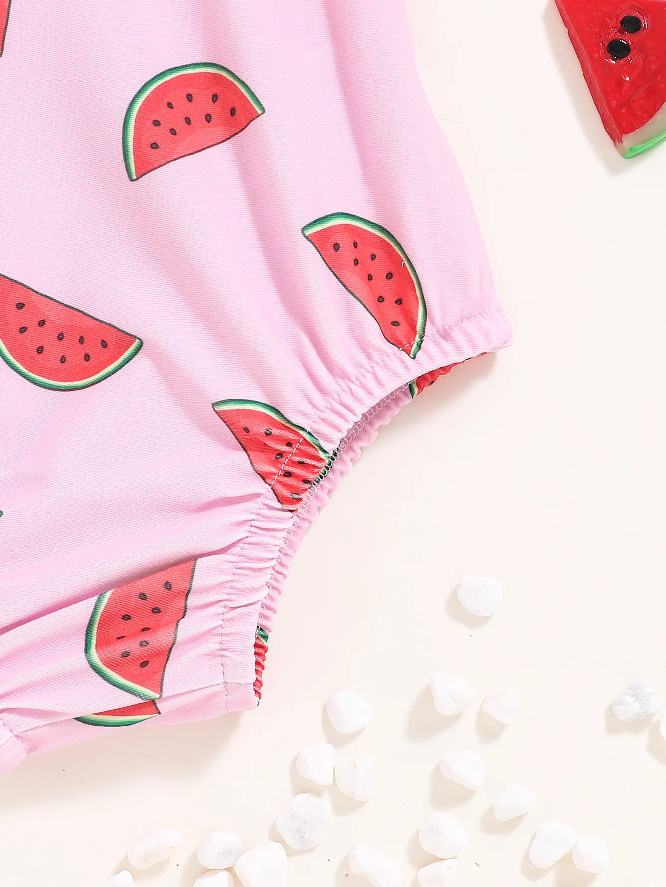 Baby girl in a cute watermelon-themed one-piece swimsuit by Baby Bubble, enjoying summer swimwear with bright, playful colors.