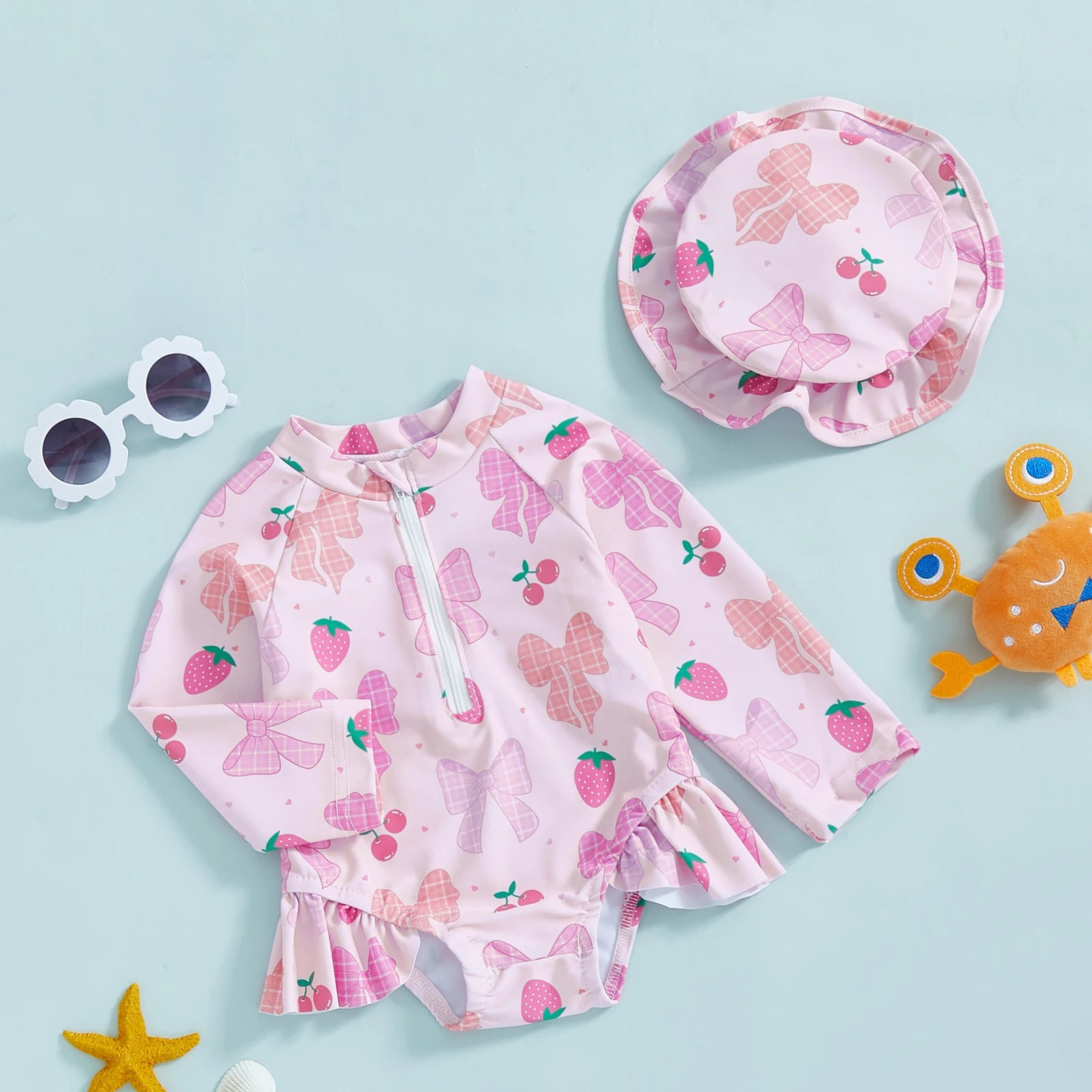 Baby girl wearing pink floral rash guard with matching hat and zip-up closure, perfect for sun protection and outdoor play.