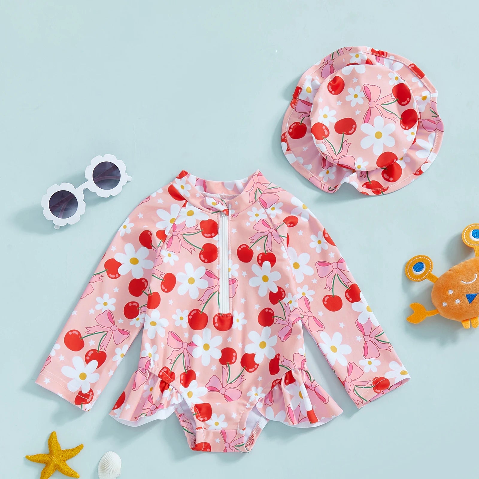 Baby girl wearing floral rash guard with hat from Baby Bubble, zip-up swimsuit, suitable for sun protection and outdoor play.