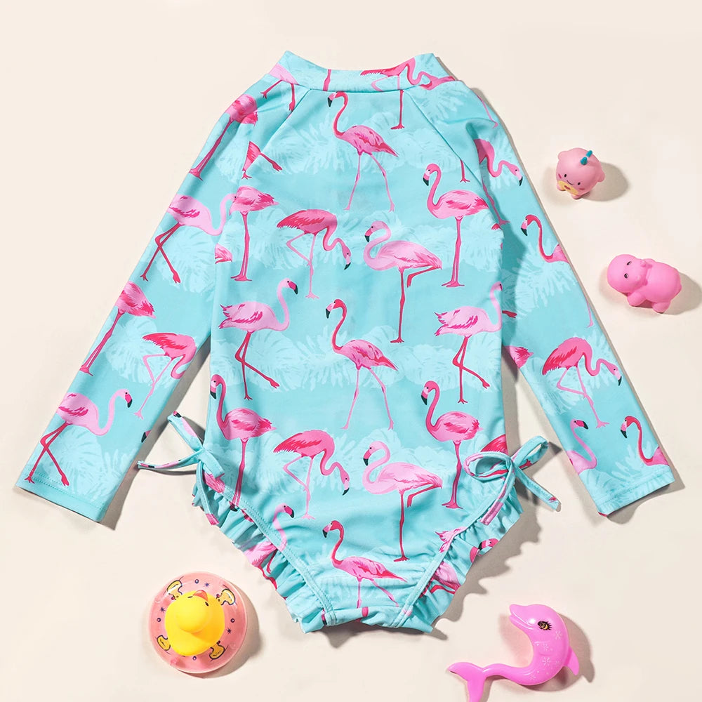 Girls Flamingo UV one-piece swimsuit with long sleeves by Baby Bubble, featuring a pink flamingo design on soft, stretchy fabric.