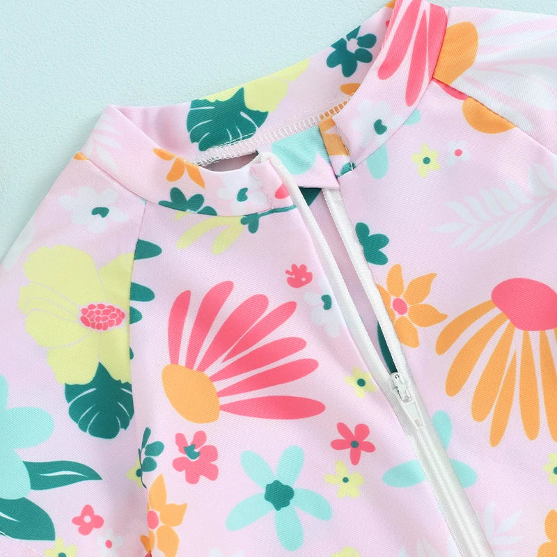 Baby girl in floral zip-up rash guard romper by Baby Bubble, showcasing colorful print and comfortable fit for sun protection.